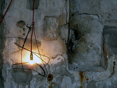 This lamp consists of a tangle of rusty wire, the light source is a gold-plated bulb suspended in a thin red